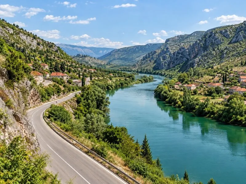 Road and river in the Neretva valley with green hills